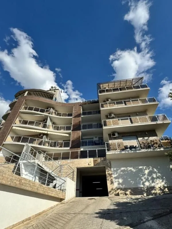 Exterior view of a residential building with terraces and driveway.