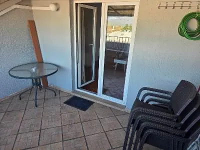 Covered terrace with a table, chairs, and access to the apartment. - image 9