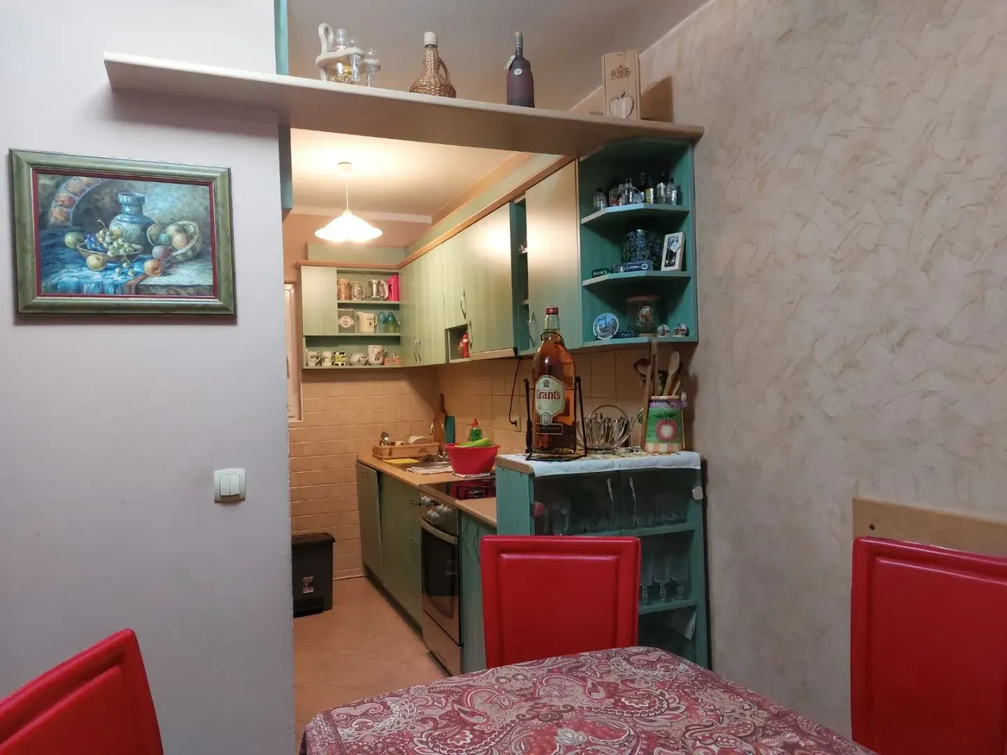 Manja kuhinja u zelenim tonovima sa trpezarijskim stolom u prvom planu.