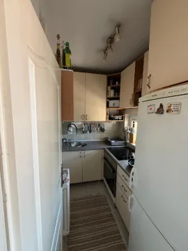 Manja opremljena kuhinja sa belim elementima i frižiderom. - image 3
