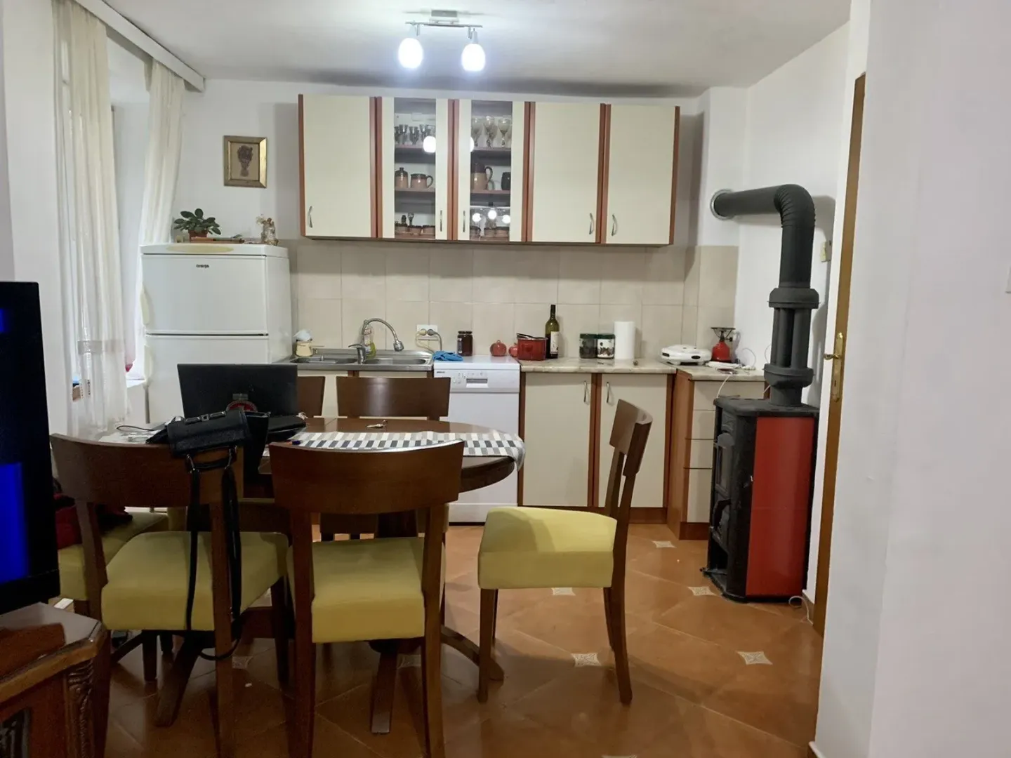 A kitchen with a dining table and a wood-burning stove.