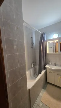 Simple bathroom featuring a bathtub, sink vanity, and mirrored cabinet. - image 6