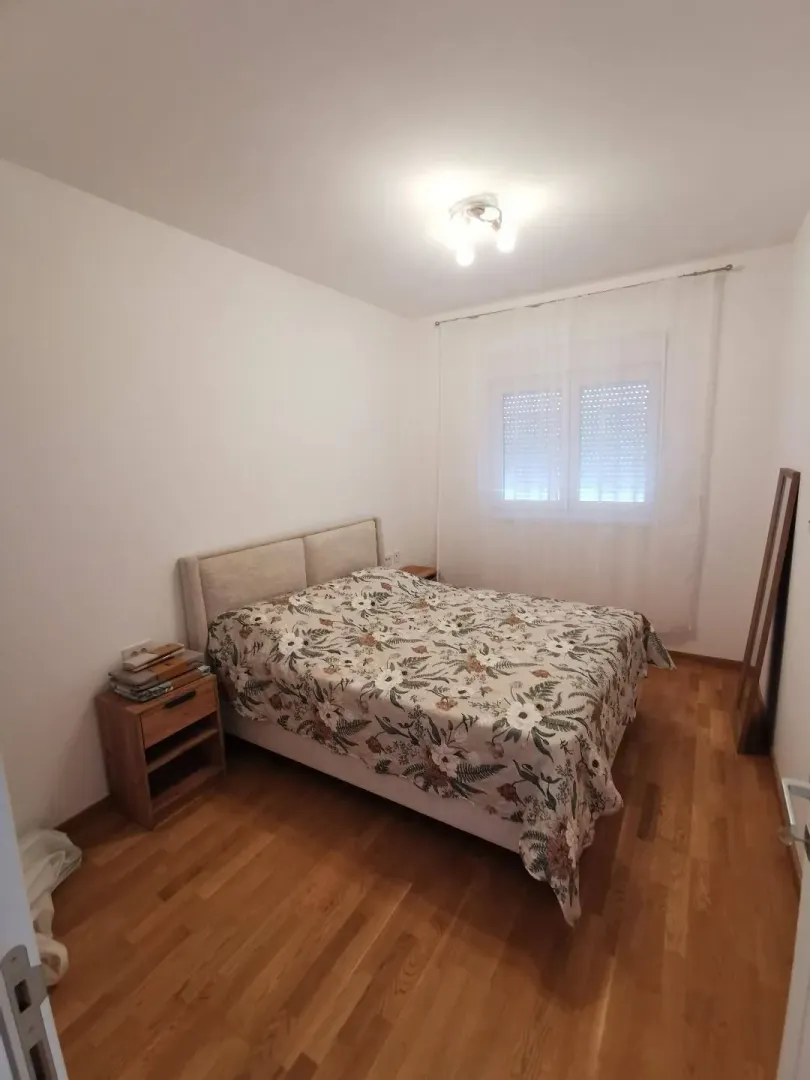 Spavaća soba sa bračnim krevetom, noćnim stočićem i prozorom.