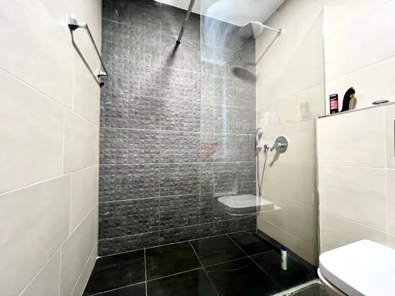 Modern bathroom with a walk-in shower and black tiles.