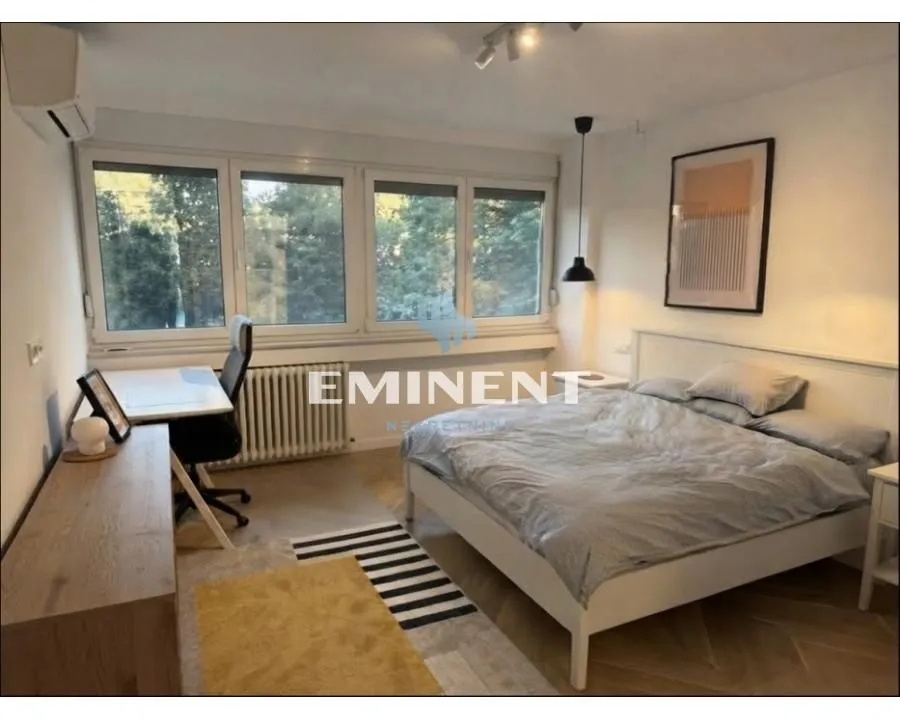 Spacious bedroom with a double bed, desk, and a large window.