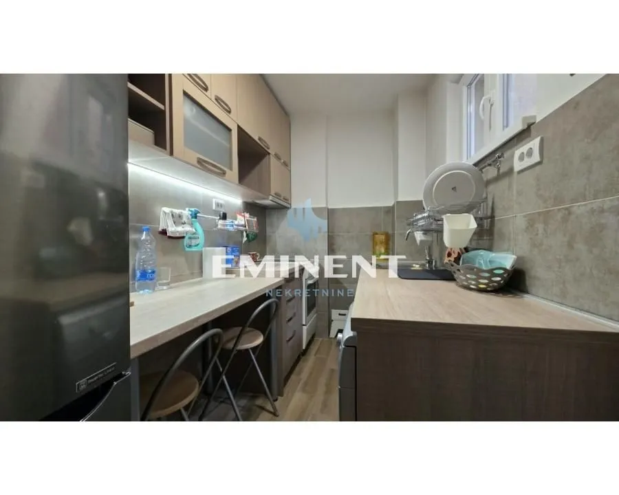 Compact equipped kitchen with wooden countertops and a bar area with chairs.