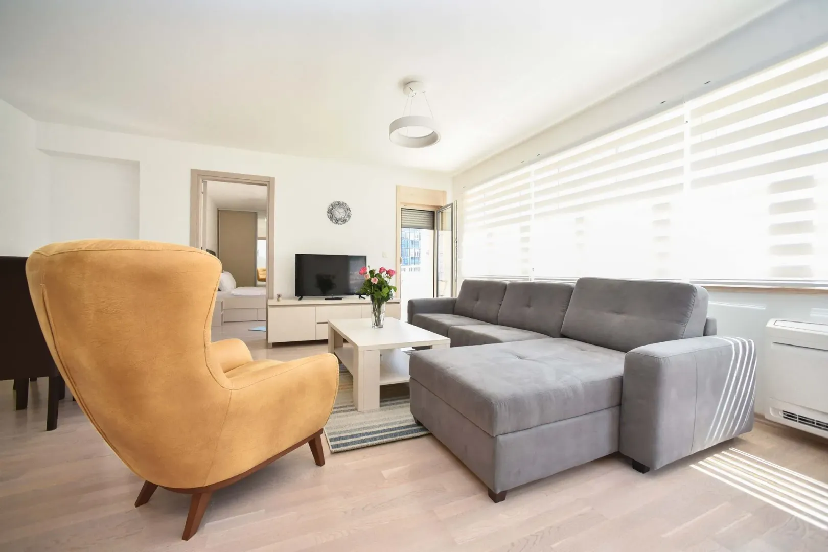 Spacious living room with a sofa, armchair, and TV.