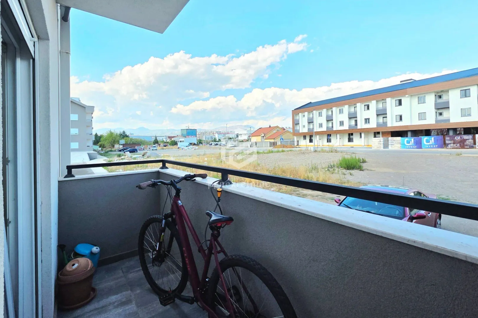 Balcony with a bicycle and a view of the surrounding buildings and landscape.