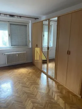 Spavaća soba sa velikim drvenim ormanom i parketom na podu. - image 7