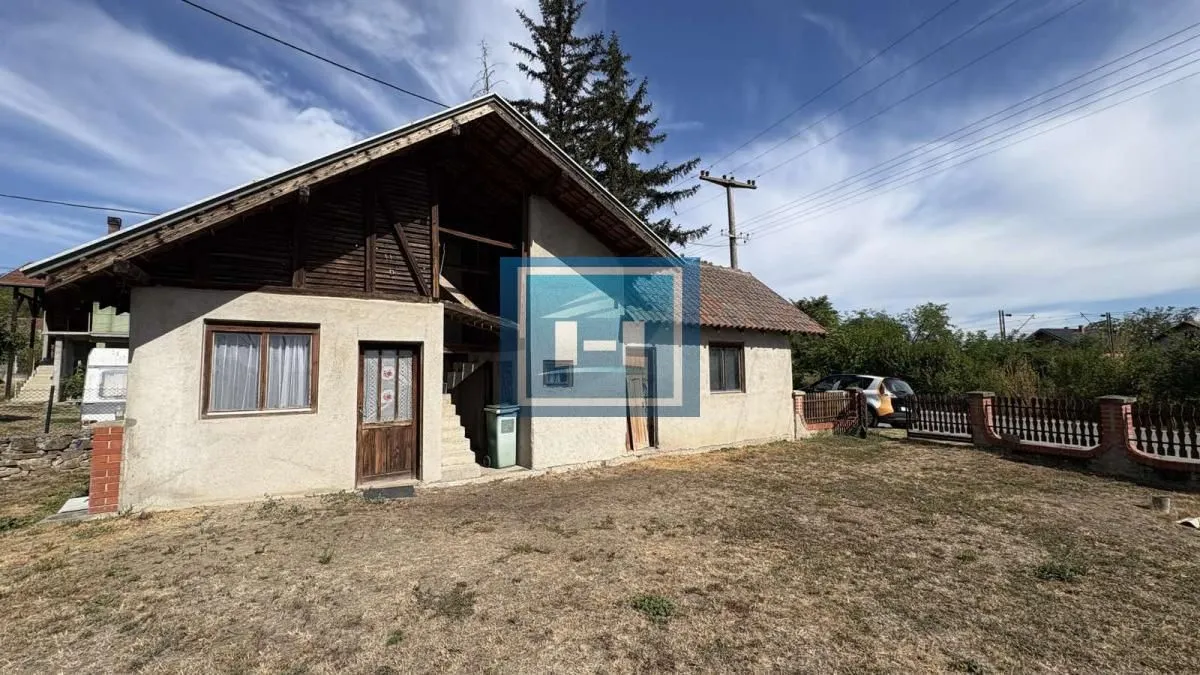 Pogled na dvorište i fasadu starije kuće sa drvenim elementima.