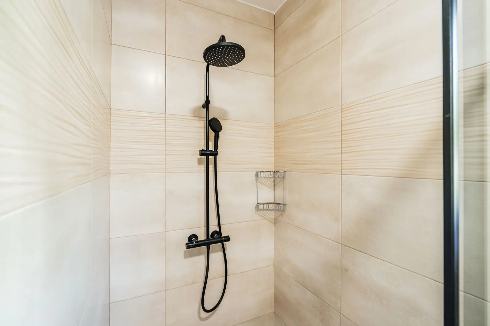 A modern shower cabin with a black shower fixture in the bathroom.