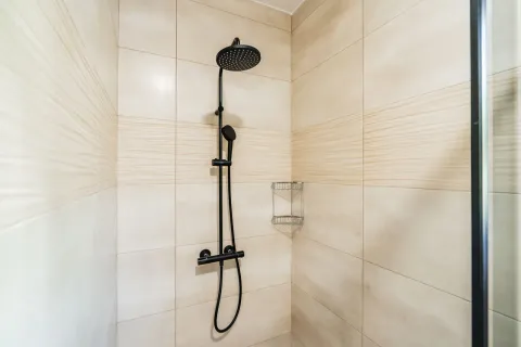A modern shower cabin with a black shower fixture in the bathroom. - image 4