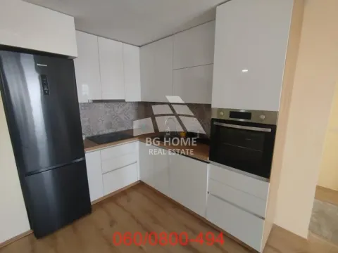 Moderna bela kuhinja sa ugrađenim aparatima i crnim frižiderom. - image 4