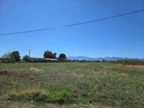 Pogled na prostrano zemljište sa travnatom površinom i udaljenim objektima. - image 2