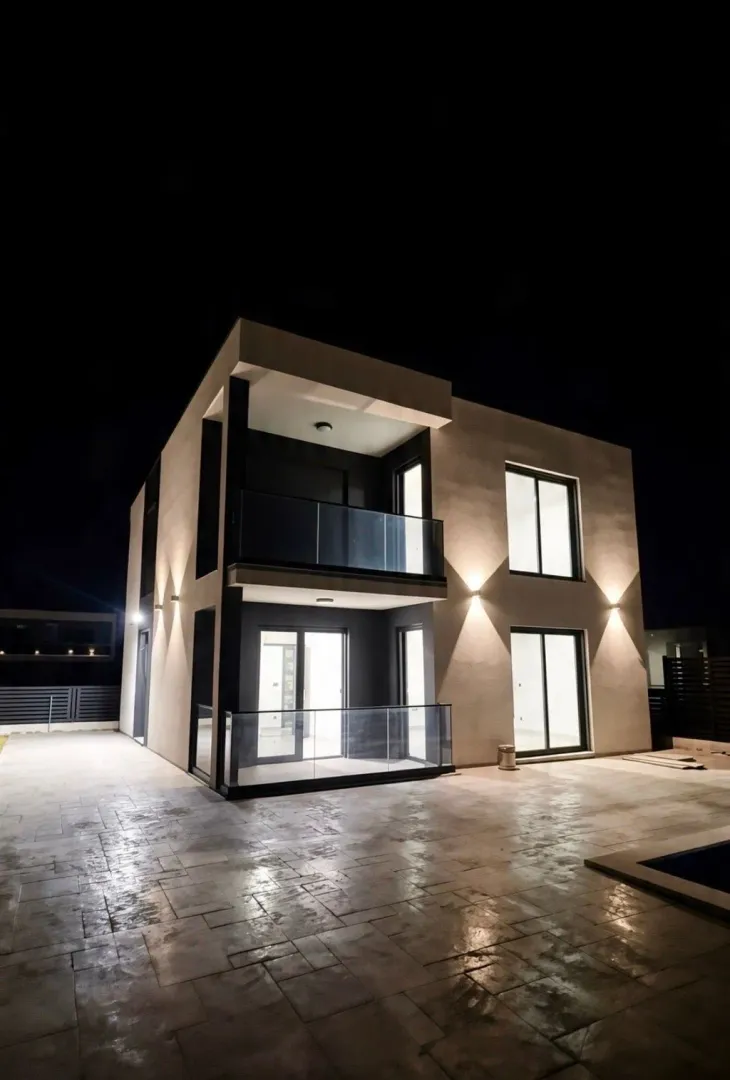 Night view of a modern house with lighting and paved courtyard.