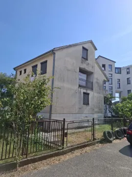 View of the exterior of the building with a yard and fence. - image 2