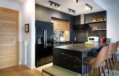 Modern kitchen with a breakfast bar, bar stools, and black cabinetry. - image 6