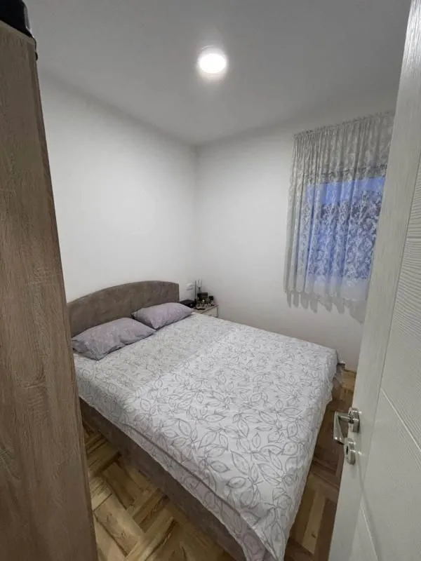 Pogled na spavaću sobu sa bračnim krevetom i prozorom.