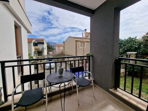 Natkriveni balkon sa garniturom za sjedenje i pogledom na okolne zgrade i dvorište. - image 11