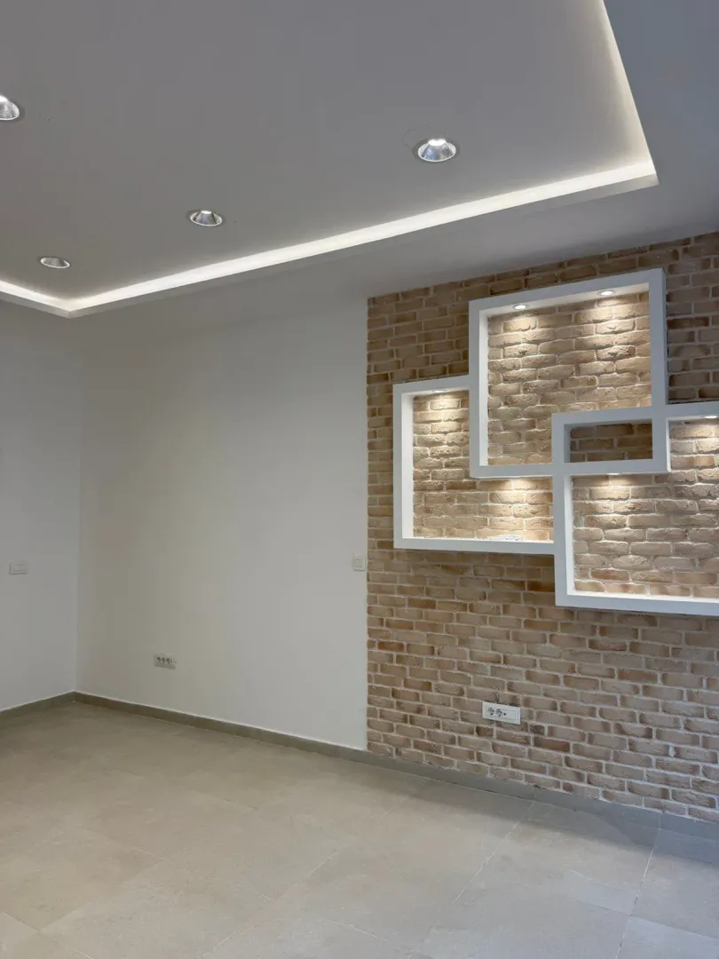 Empty room with a decorative brick wall and recessed lighting.