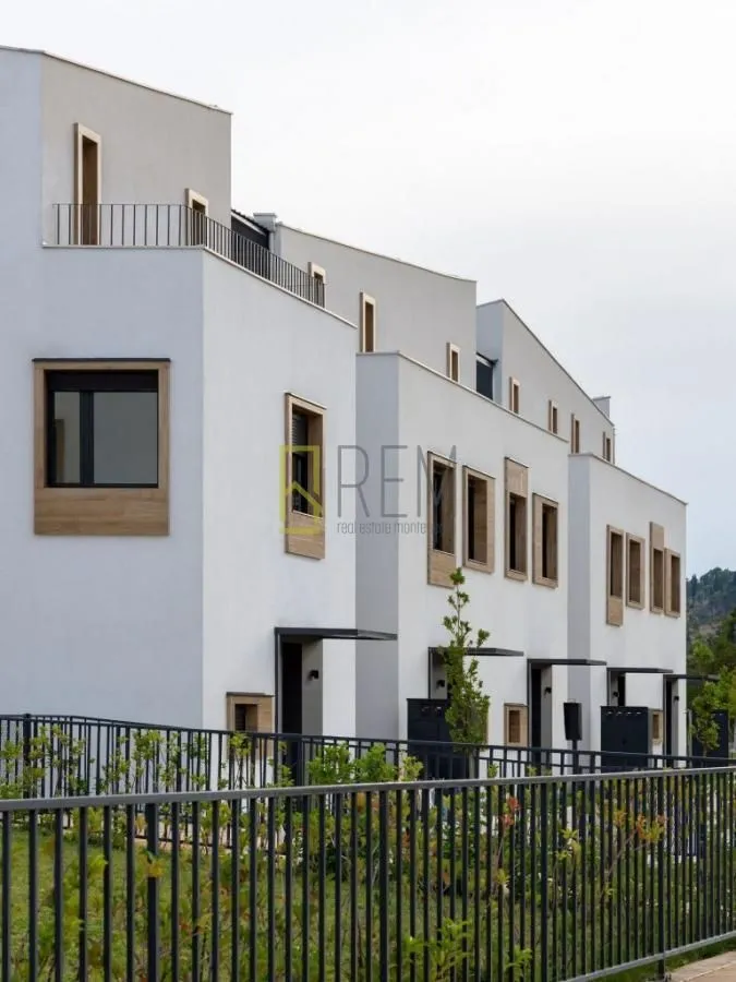 Eksterijer modernih višestambenih zgrada sa uređenom ogradom i dvorištem.