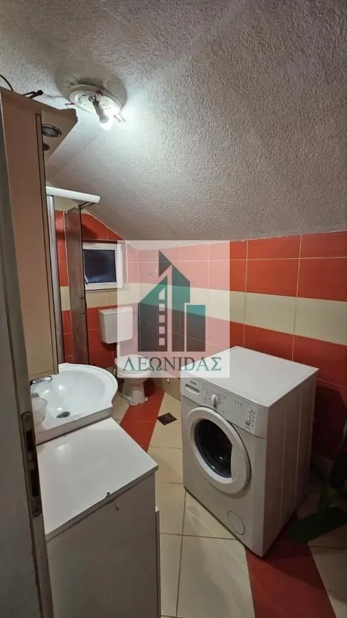 Bathroom with a shower cabin, washbasin, toilet, and washing machine.