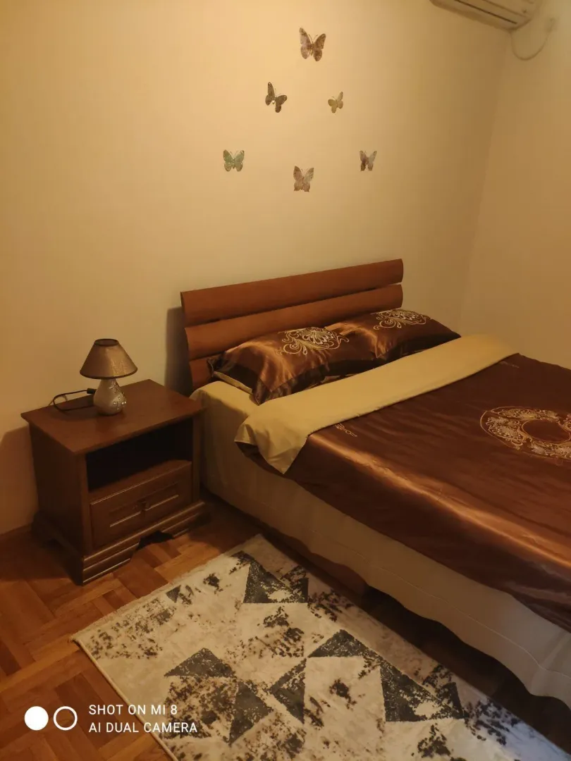 Spavaća soba sa bračnim krevetom i noćnim stolom.