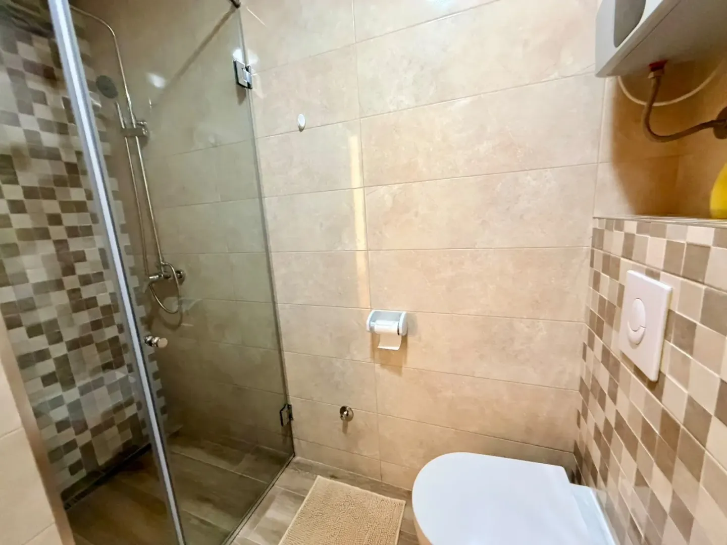 Moderne kupatilo sa tuš kabinom i ugradnom šoljom.