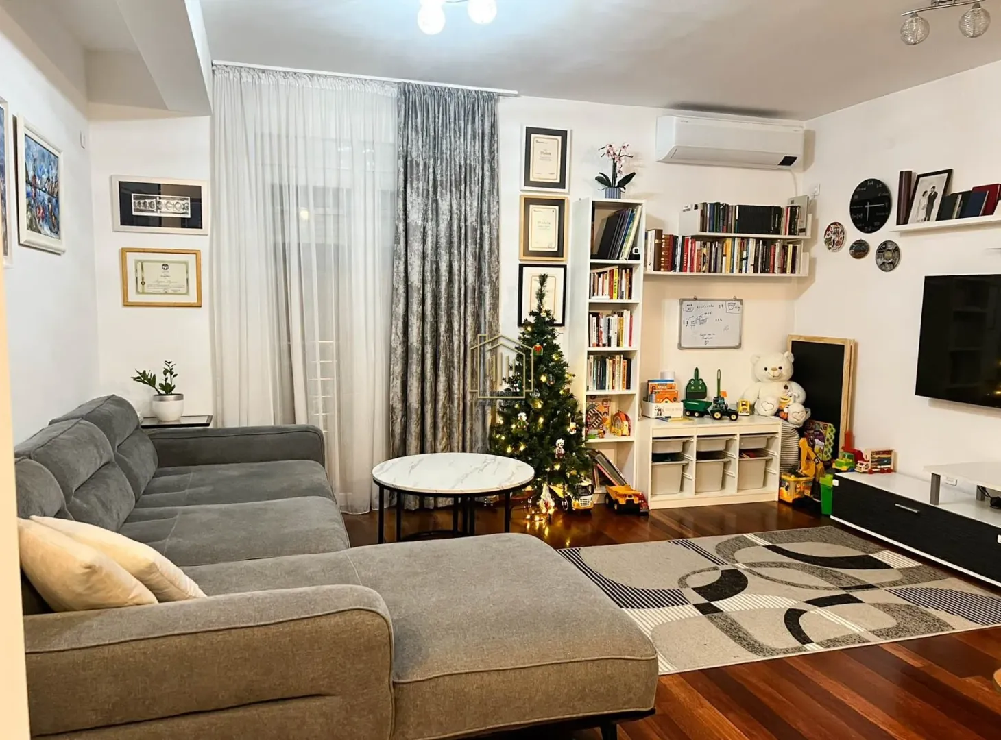 Living room with a sectional sofa, bookshelves, and a television.