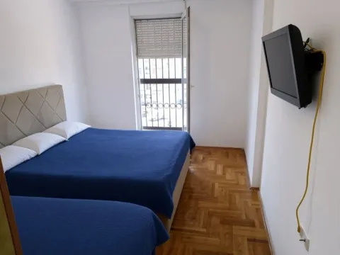 Spavaća soba sa dva kreveta, parketom i zidnim televizorom. - image 7