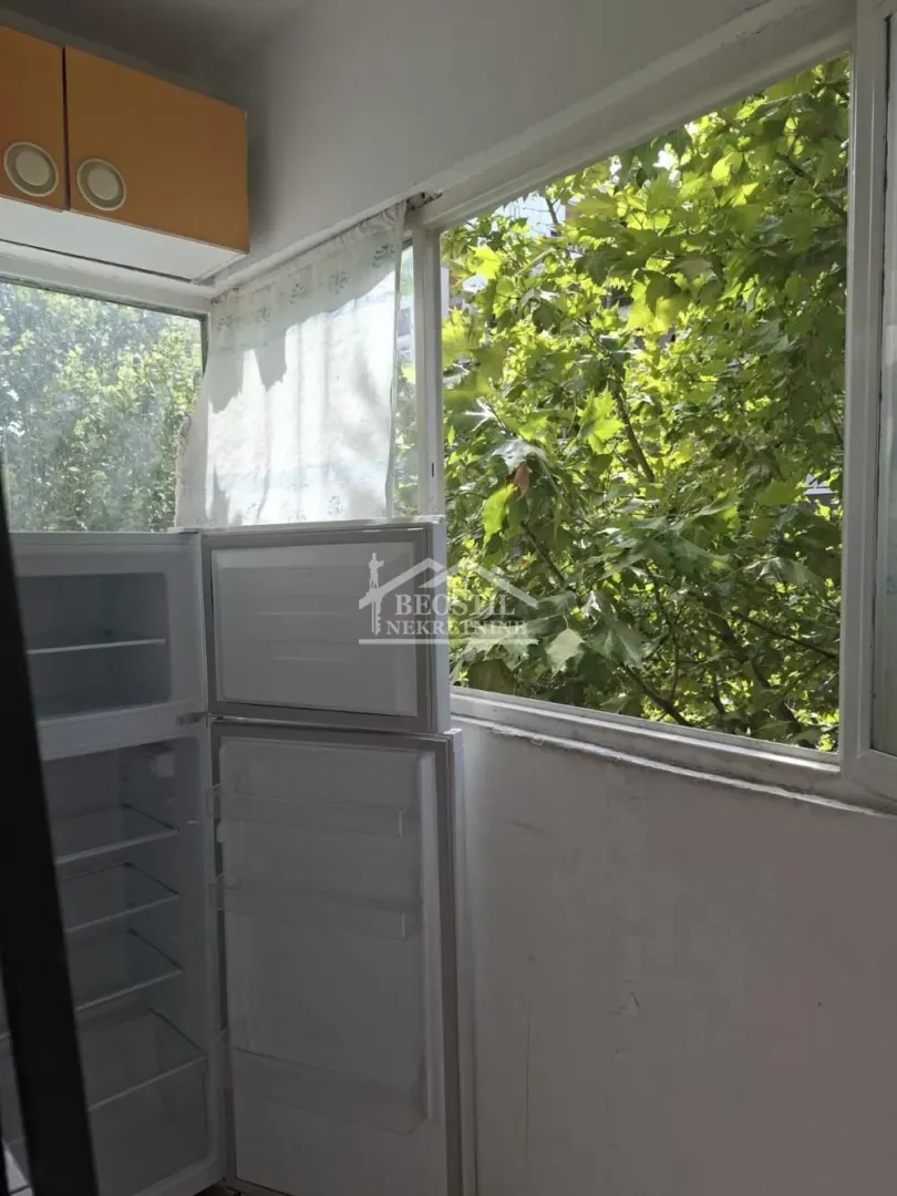 Kitchen with an open window and a refrigerator near the wall.