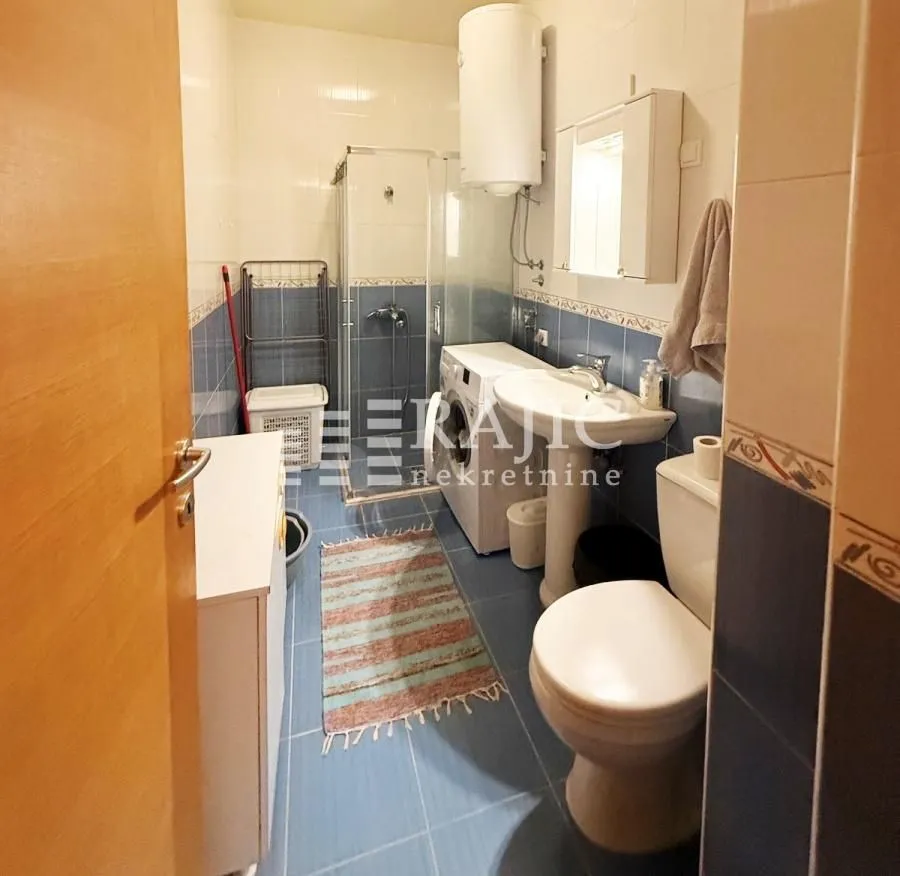 Equipped bathroom with a shower cabin, washbasin, washing machine, and toilet.