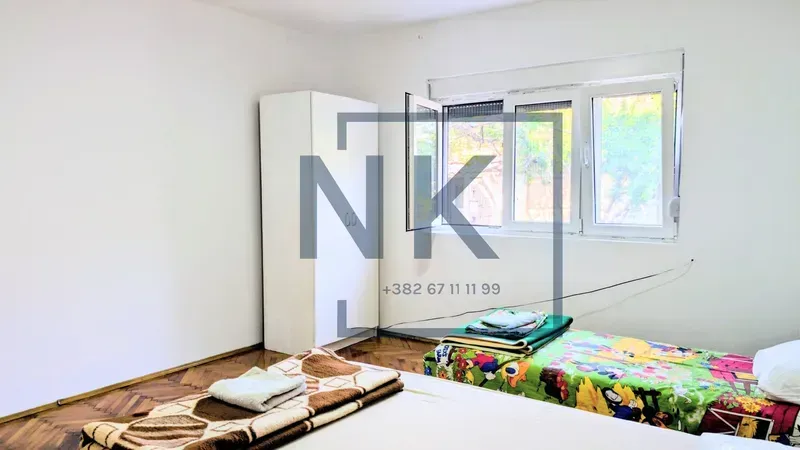 Furnished bedroom with two beds and a wardrobe.
