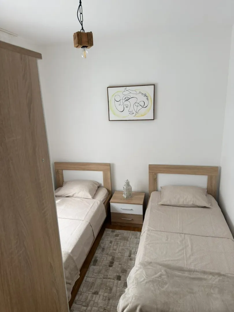 Manja spavaća soba sa dva odvojena kreveta i noćnim ormarićem.