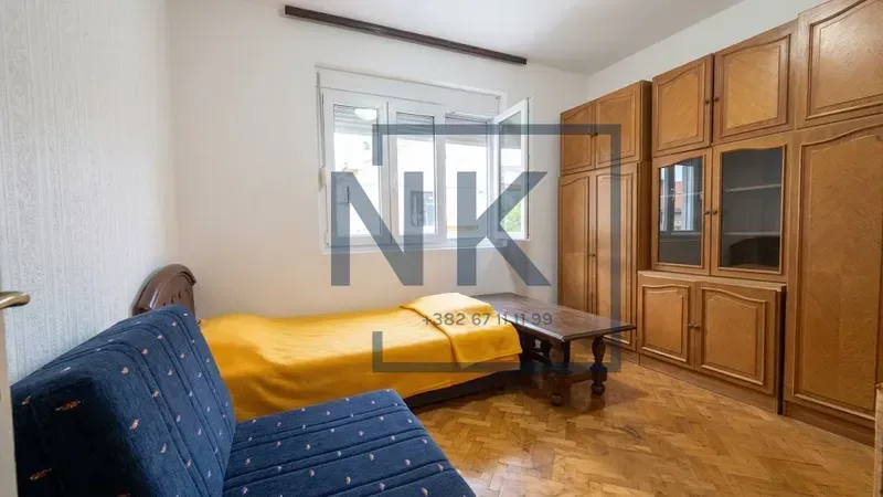 Furnished bedroom with a bed, an armchair and wooden wardrobes.