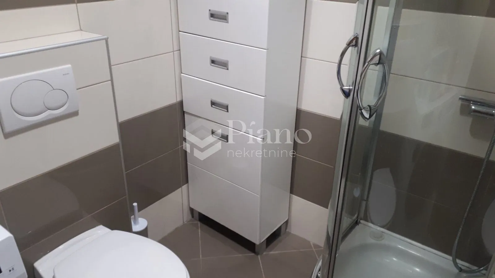 View of the bathroom with sanitary fixtures, a cabinet, and a shower cabin.