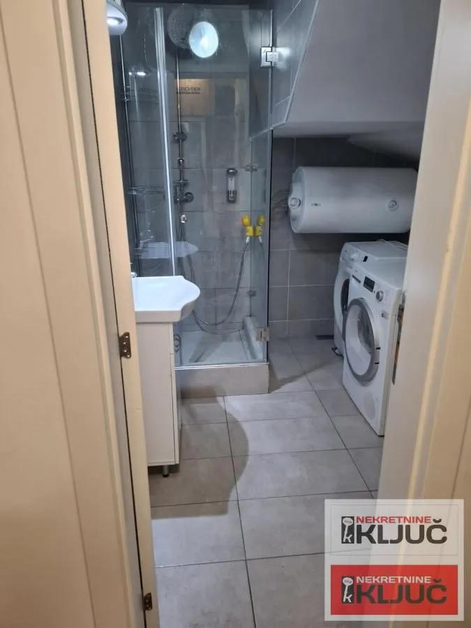 Manje kupatilo sa tuš kabinom i veš mašinom.