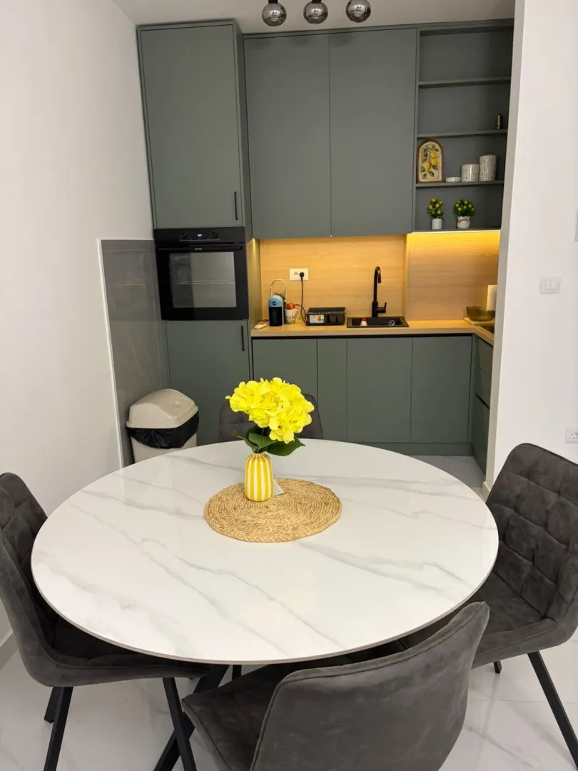 Dining area with a round table and a kitchen in the background.