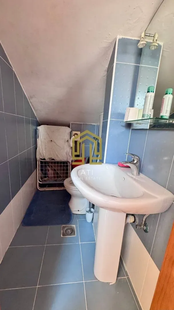 Manje kupatilo sa umivaonikom, WC šoljom i plavim pločicama.