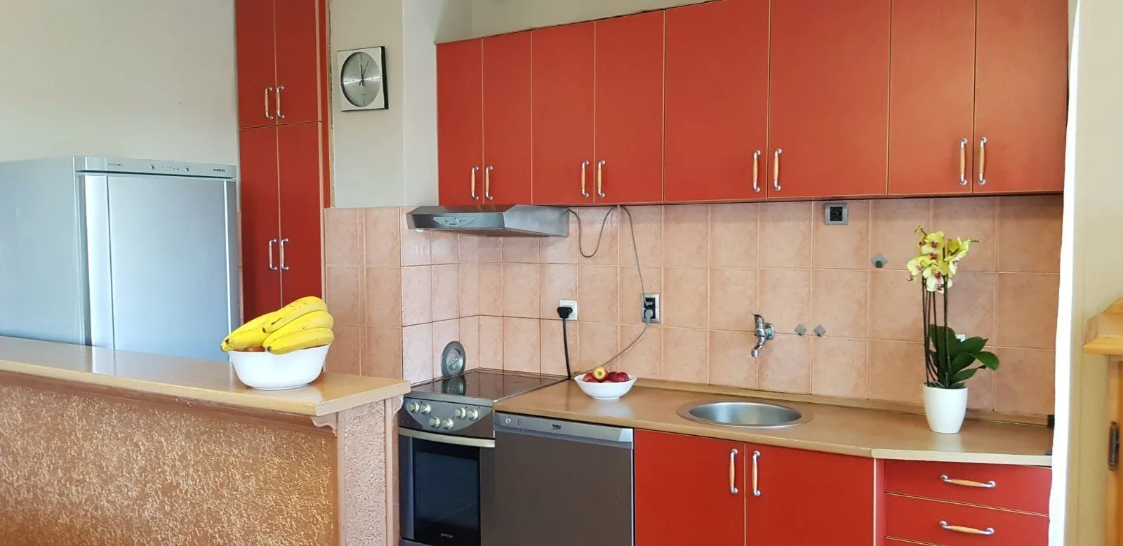 Kuhinja sa narandžastim elementima.
