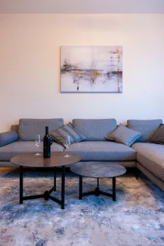 Living room with a gray sectional sofa, coffee tables, and an art painting on the wall. - image 2
