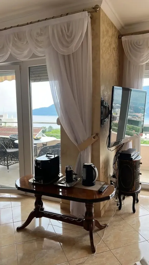 Dnevni boravak sa stolom za kafu, televizorom i izlazom na terasu sa pogledom na more.