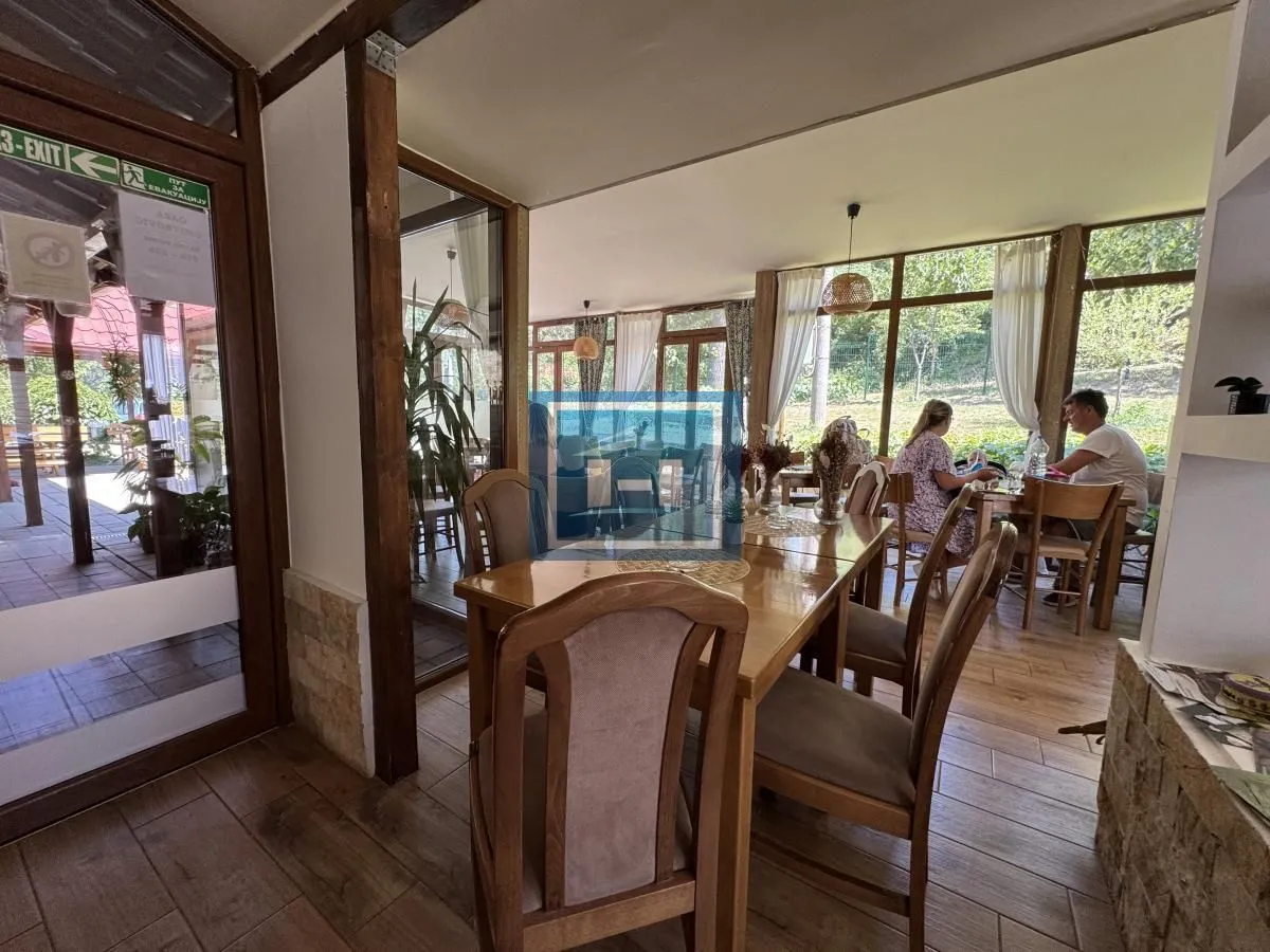 Spacious dining area with a wooden table and chairs and a view of nature.