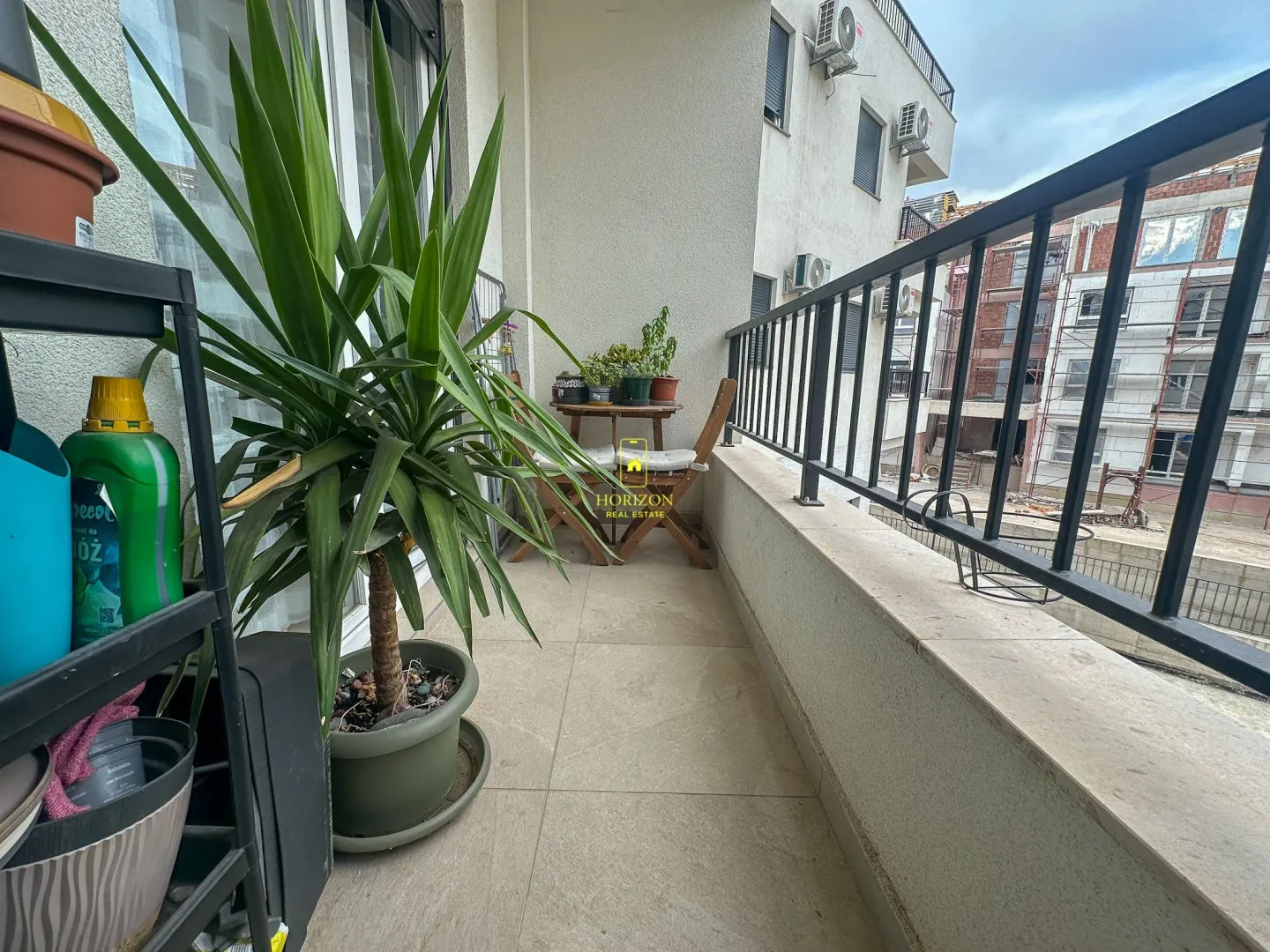 Namješten balkon sa garniturom za sjedenje i velikom ukrasnom biljkom.