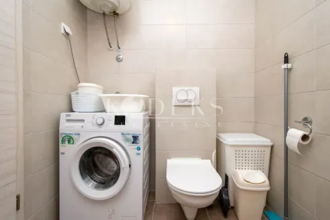 Bathroom equipped with a toilet, washing machine, and laundry baskets. - image 7