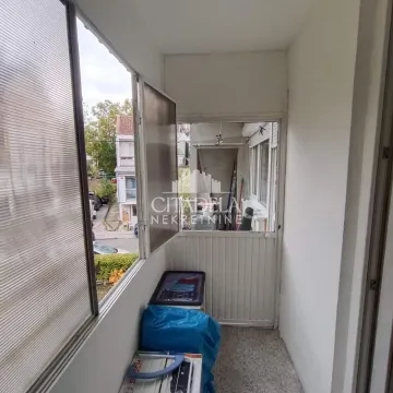 Zastakljeni balkon sa pogledom na ulicu i okolne zgrade. - image 6