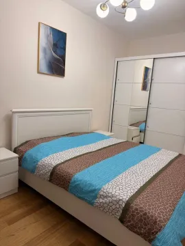 Svijetla spavaća soba sa bračnim krevetom i bijelim ormarom sa ogledalom. - image 9