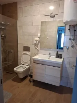 Modern bathroom with a walk-in shower, vanity sink, and toilet. - image 4