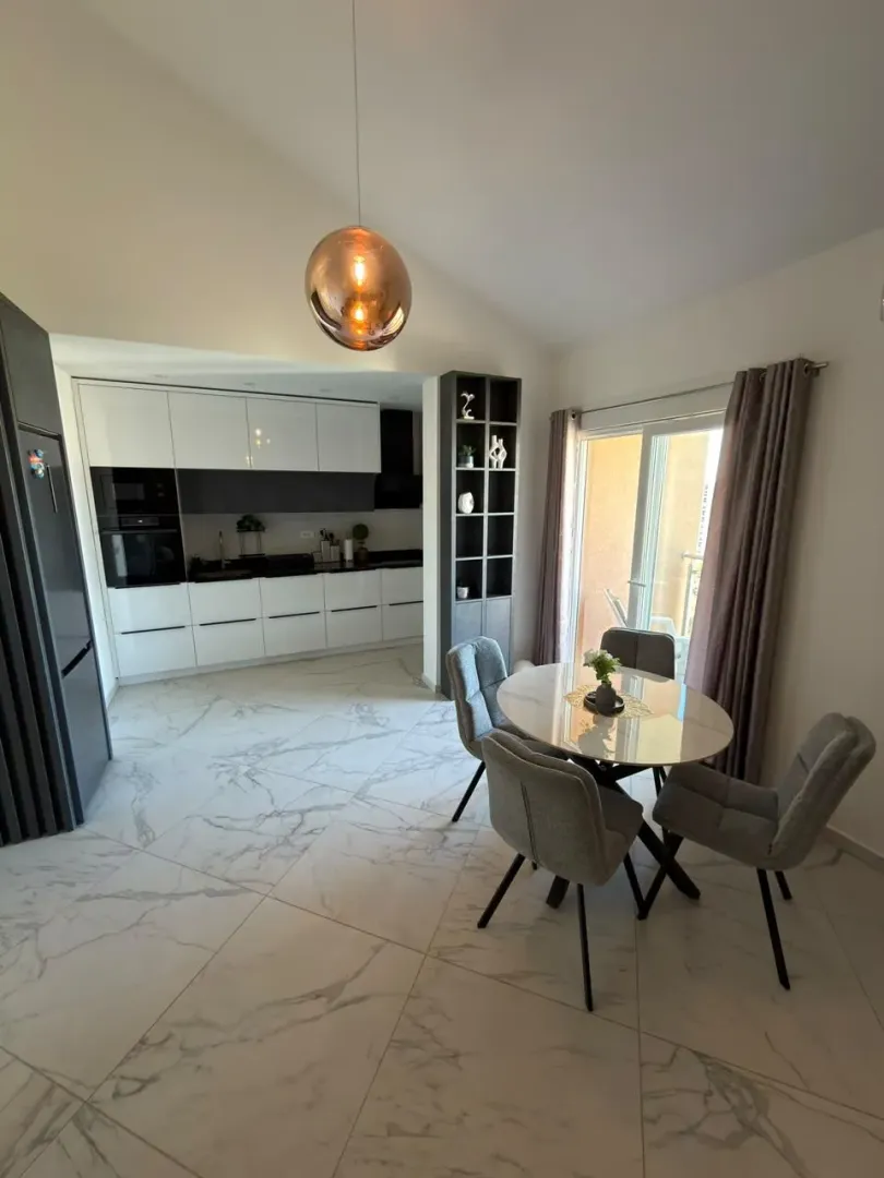 Modern kitchen with dining area and marble-effect tiles.