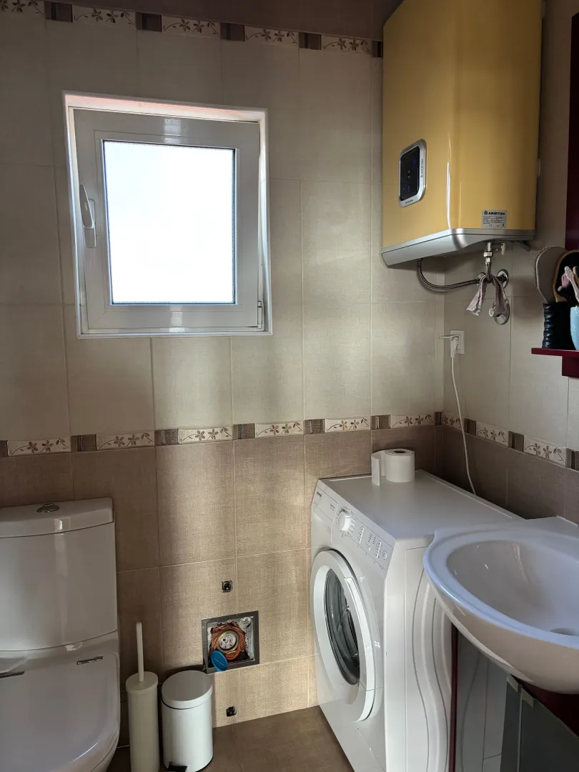 Small bathroom equipped with sanitary fixtures, a washing machine, and a yellow water heater.